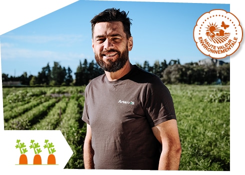 Portrait d’un producteur de carottes de Provence dans son champ, accompagné du logo du label Haute Valeur Environnementale superposé sur l’image.